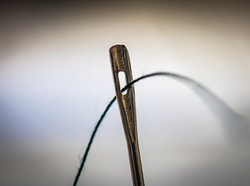 Close up of thread going through a needle