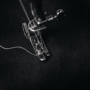 Close up image of stitching machine creating a black garment