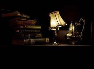 Dark image of books laying on a research desk with a shimmering lamp